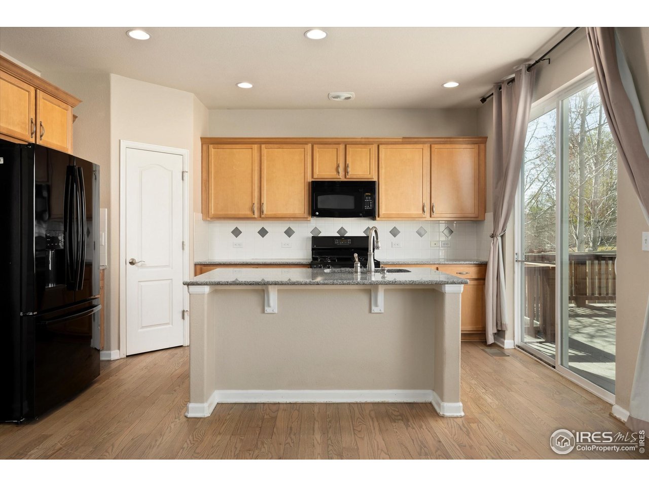 4874 Sandy Ridge Avenue Firestone, CO 80504 - Photo 7 of 35 a kitchen with stainless steel appliances granite countertop a refrigerator a stove a sink and a window with wooden floor