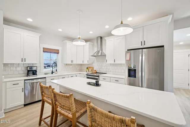 a kitchen with kitchen island a stove a sink a refrigerator and white cabinets with wooden floor