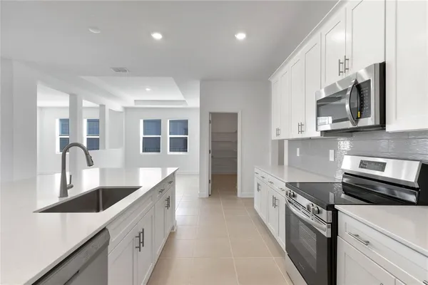 a large kitchen with stainless steel appliances granite countertop a lot of counter space and a sink