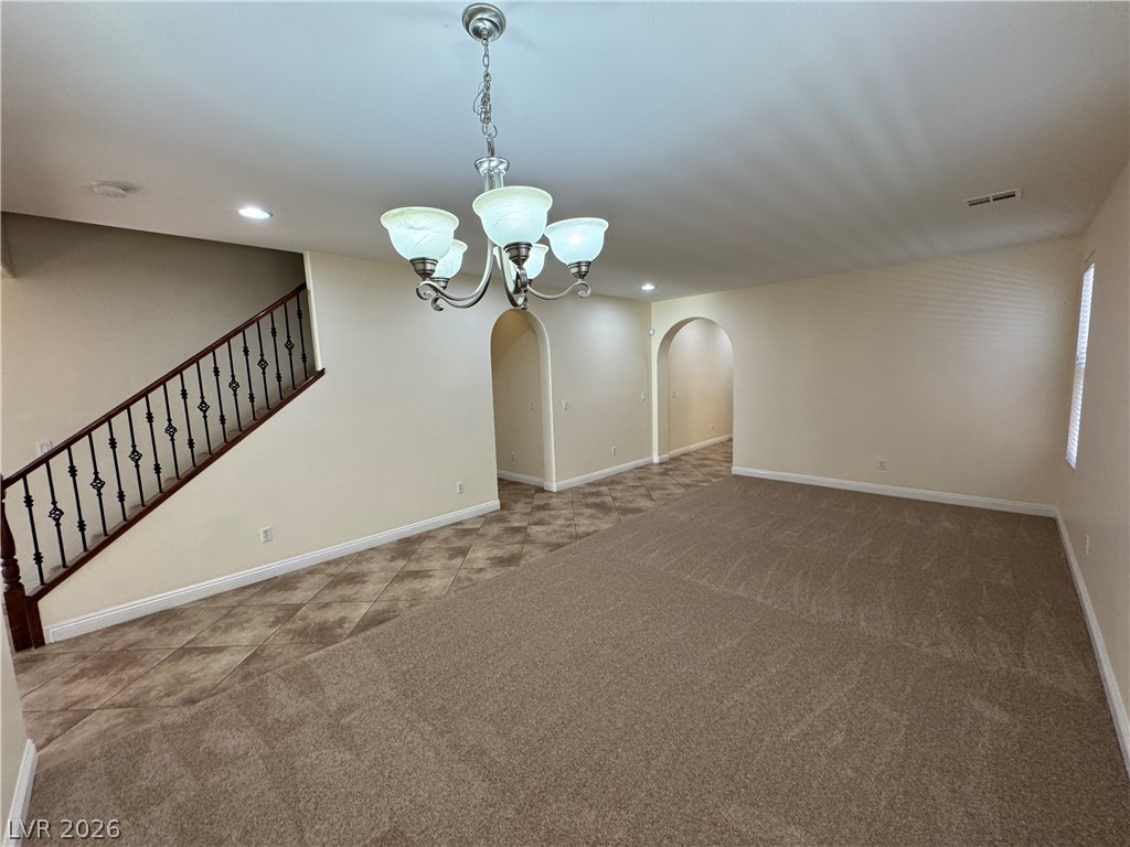 1333 Jamesbury Road Las Vegas, NV 89135 - Photo 9 of 43 A graceful staircase with intricate ironwork highlights this welcoming interior, connecting spacious rooms with distinct flooring.