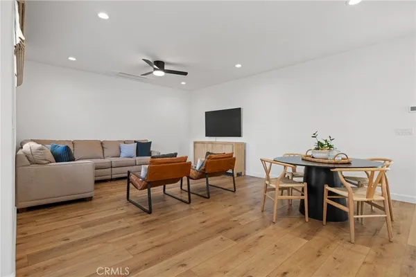 a living room with furniture kitchen view and a wooden floor
