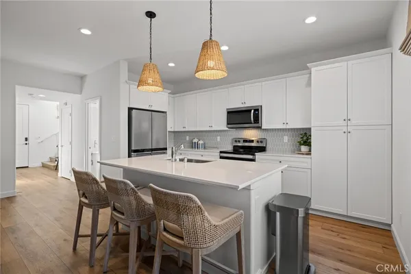 a kitchen with a sink a refrigerator a stove and chairs with wooden floor