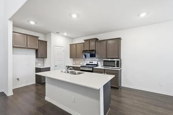 a kitchen with a sink a stove a refrigerator a center island and a window