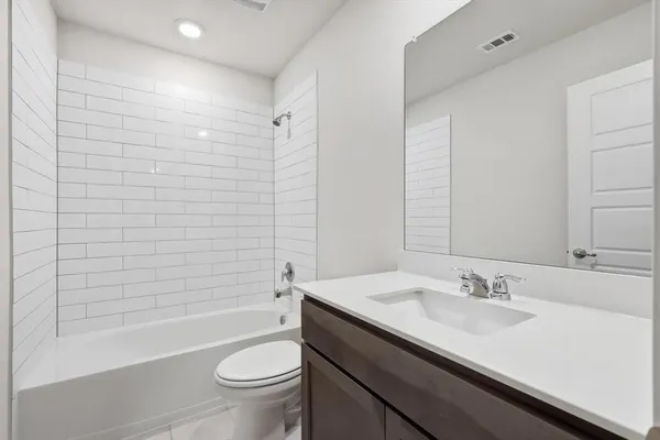 a bathroom with a granite countertop sink a toilet a mirror and bathtub