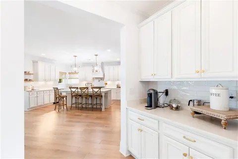 a dining room with wooden floor a chandelier a wooden table and chairs
