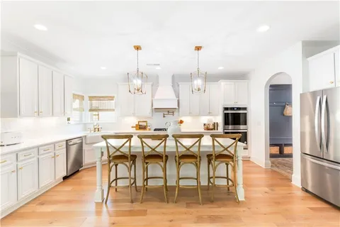 a kitchen with stainless steel appliances granite countertop a stove top oven a sink a dining table and chairs with wooden floor