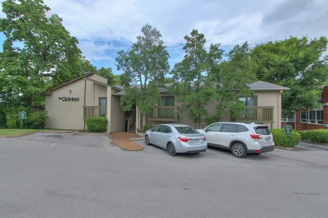 a front view of a house with cars parked on the road