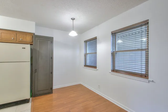 a view of an empty room with window and wooden floor