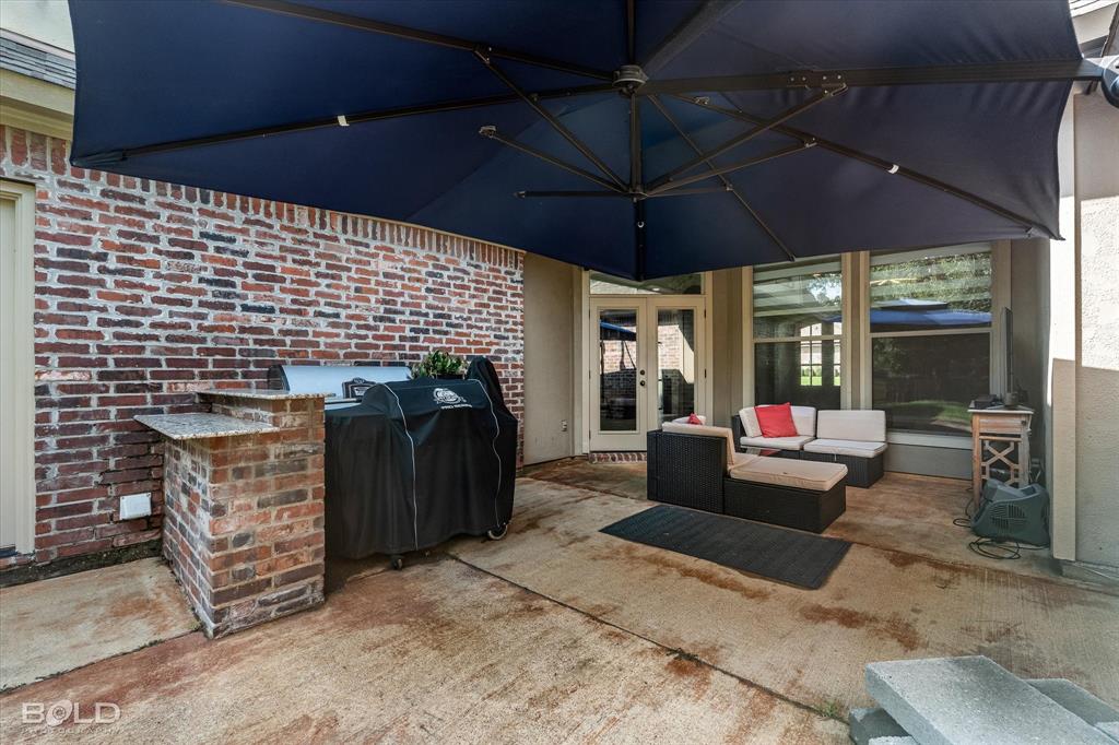 2220 Forest Hills Boulevard Haughton, LA 71037 - Photo 6 of 40 Expansive patio featuring a built-in brick and stone-finish countertop, concrete flooring, and French doors providing access indoors