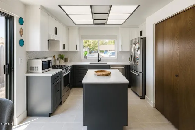 a kitchen with stainless steel appliances a stove a refrigerator a sink a dining table and chairs