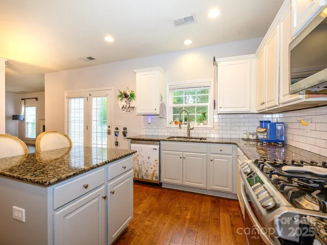 a kitchen with granite countertop a sink stove and cabinets
