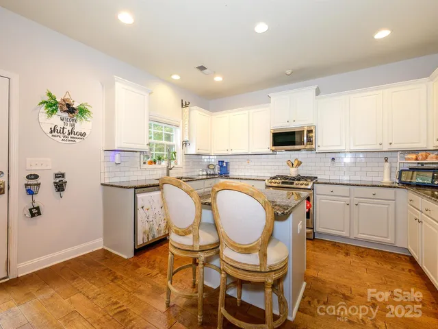 a kitchen with a sink a stove a microwave a dining table and chairs