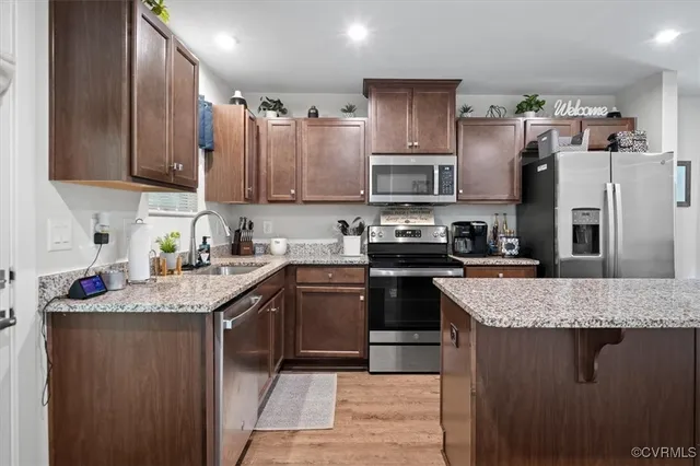 a kitchen with stainless steel appliances granite countertop a sink dishwasher stove top oven and refrigerator