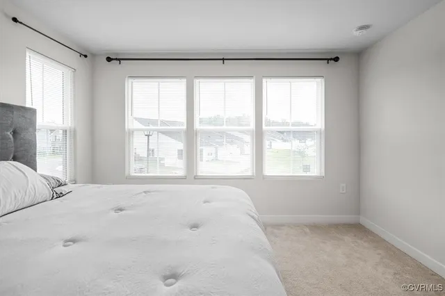 a large white bed sitting in a bedroom next to a window