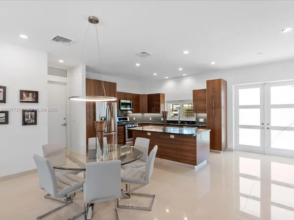 a kitchen with stainless steel appliances kitchen island granite countertop a refrigerator and a stove top oven with wooden floor