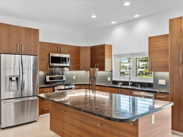a kitchen with stainless steel appliances granite countertop a sink a stove and a refrigerator