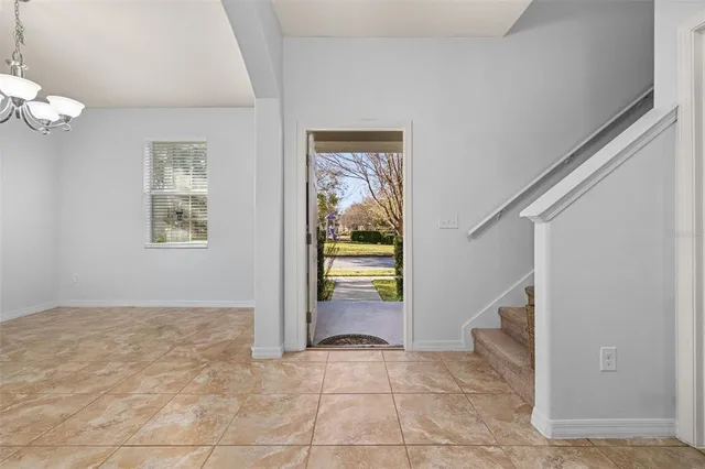 an empty room with a chandelier fan and windows