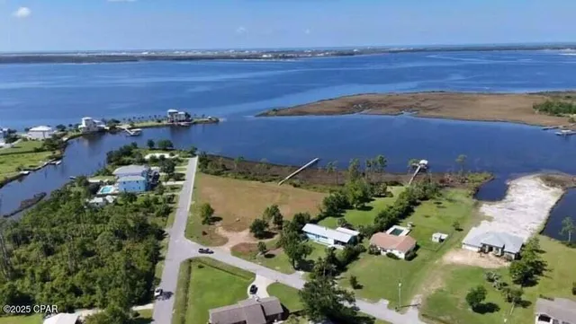 an aerial view of ocean and residential houses with outdoor space