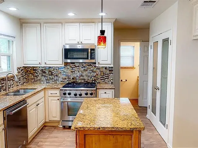 a kitchen with stainless steel appliances granite countertop a stove sink and cabinets