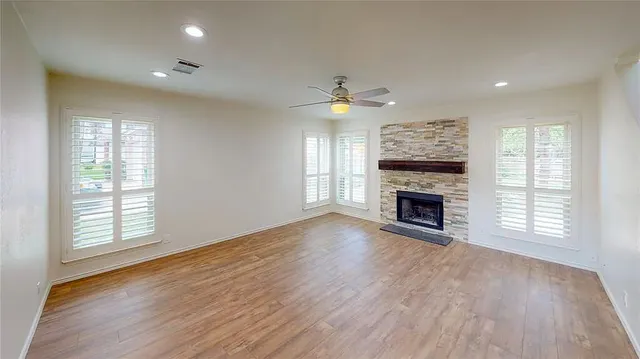 an empty room with windows fireplace and wooden floor