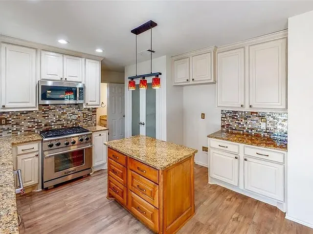 a kitchen with stainless steel appliances granite countertop a stove and a refrigerator