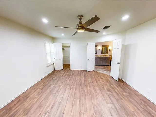 a view of empty room with wooden floor and ceiling fan