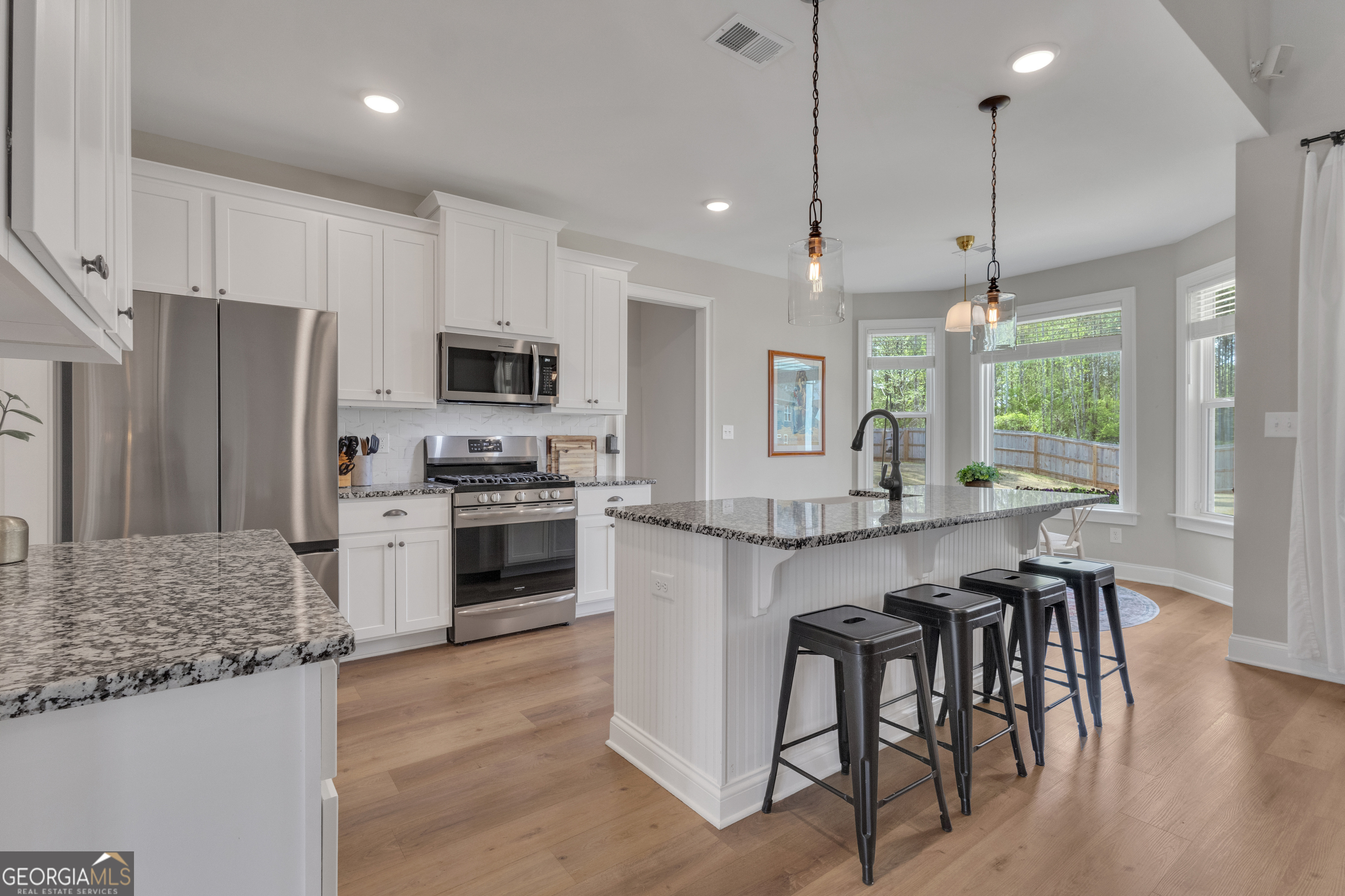 50 Cushing Street Senoia, GA 30276 - Photo 13 of 72 a kitchen with stainless steel appliances granite countertop a stove top oven a refrigerator a sink and a dining table with wooden floor