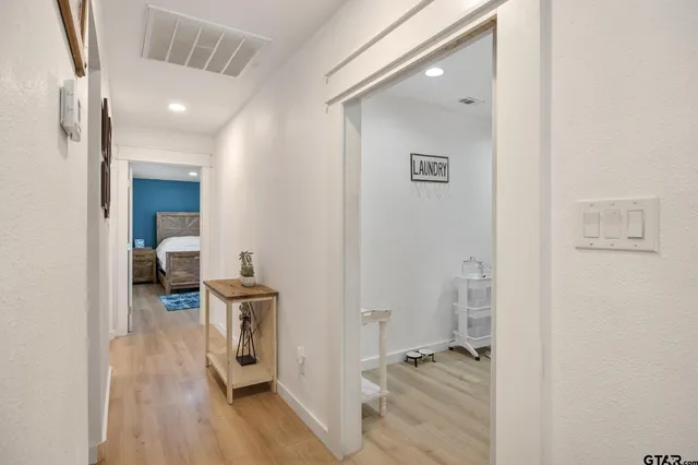 a hall way with furniture a wooden floor and a ceiling fan