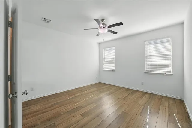 a view of empty room with wooden floor and fan