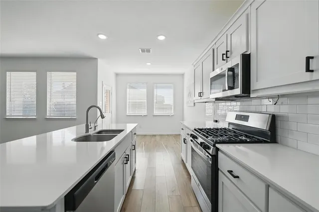 a kitchen with stainless steel appliances granite countertop a sink stove and cabinets