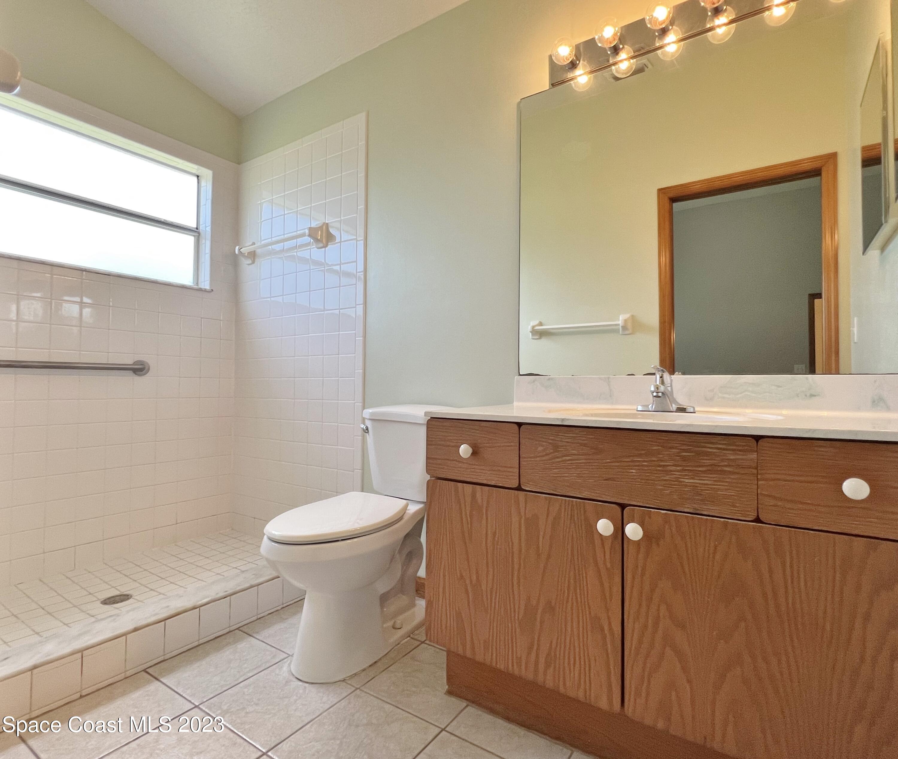 1054 South Fork Circle Melbourne, FL 32901 - Photo 5 of 16 a bathroom with a granite countertop sink toilet and mirror