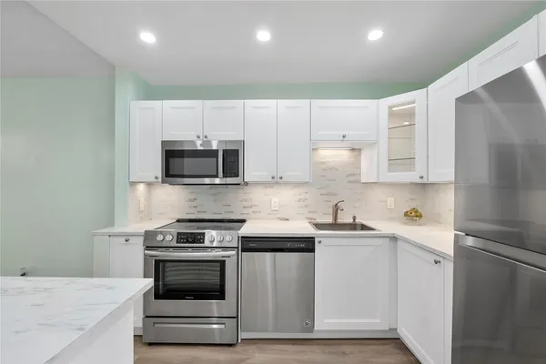 a kitchen with granite countertop white cabinets and stainless steel appliances