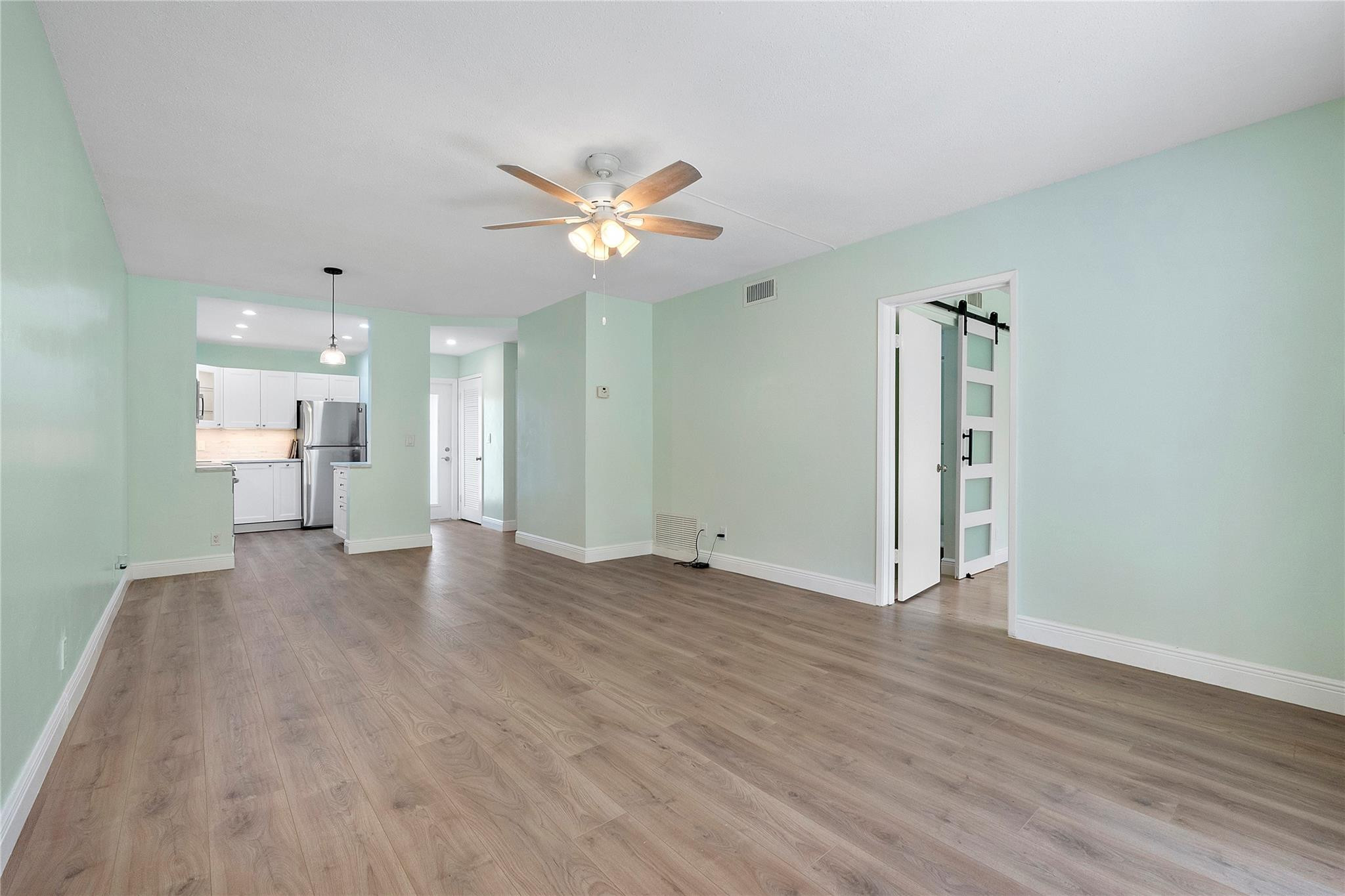 1951 Northeast 39th Street, Unit 156 Lighthouse Point, FL 33064 - Photo 10 of 43 a view of an empty room with wooden floor and a ceiling fan