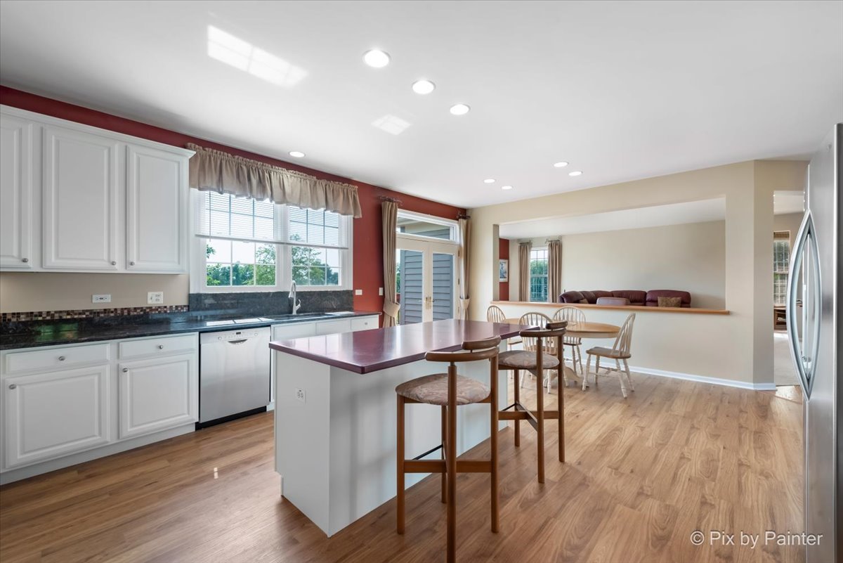 8475 Watson Circle Lakewood, IL 60014 - Photo 15 of 49 a kitchen with stainless steel appliances granite countertop wooden floor a dining table and chairs