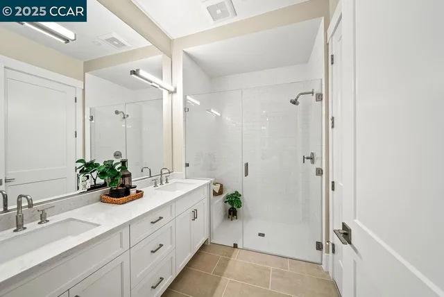 a bathroom with a double vanity sink mirror and shower