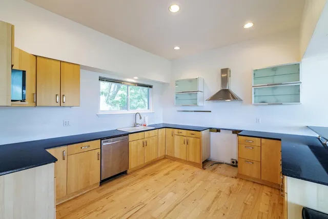 a kitchen with stainless steel appliances granite countertop a sink and cabinets with wooden floor