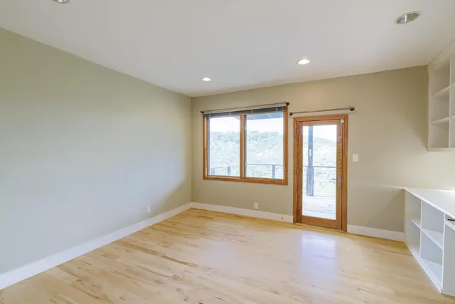 a view of an empty room with wooden floor and a window