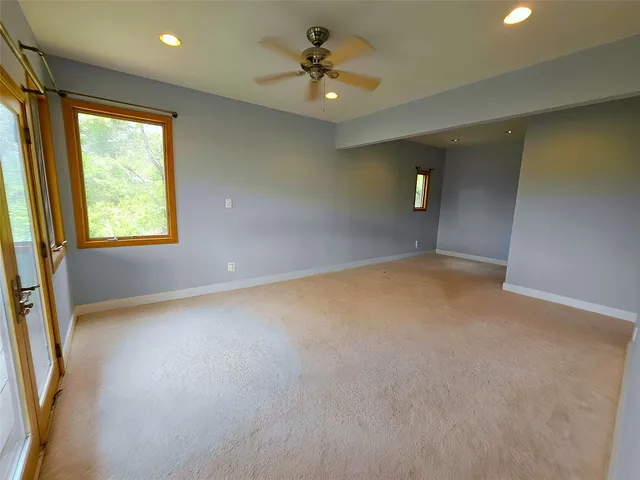 an empty room with a window and a ceiling fan