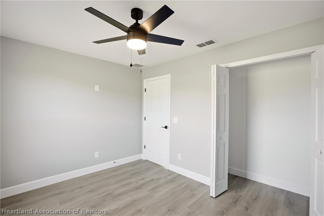 1117 Mc Donald Road Wauchula, FL 33873 - Photo 26 of 36 an empty room with wooden floor and ceiling fan
