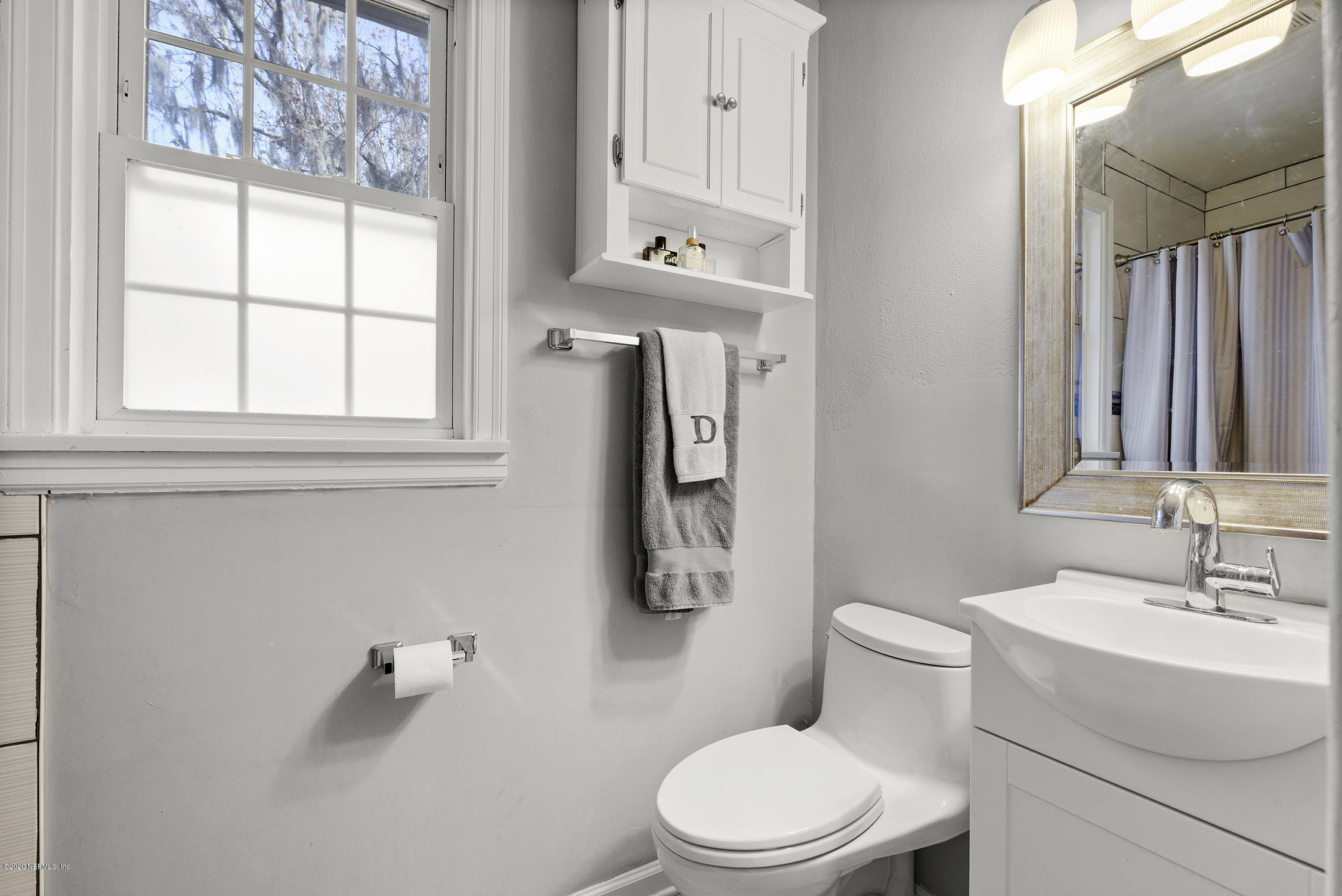 3847 Gadsden Road Jacksonville, FL 32207 - Photo 20 of 29 a bathroom with a toilet a sink a mirror and a window