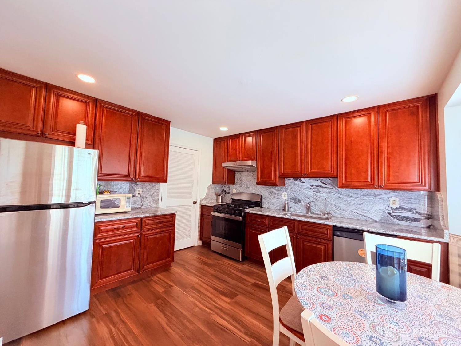 918 Plymouth Road North Brunswick, NJ 08902 - Photo 13 of 30 a kitchen with stainless steel appliances granite countertop a refrigerator a sink dishwasher a stove and a dining table with wooden floor
