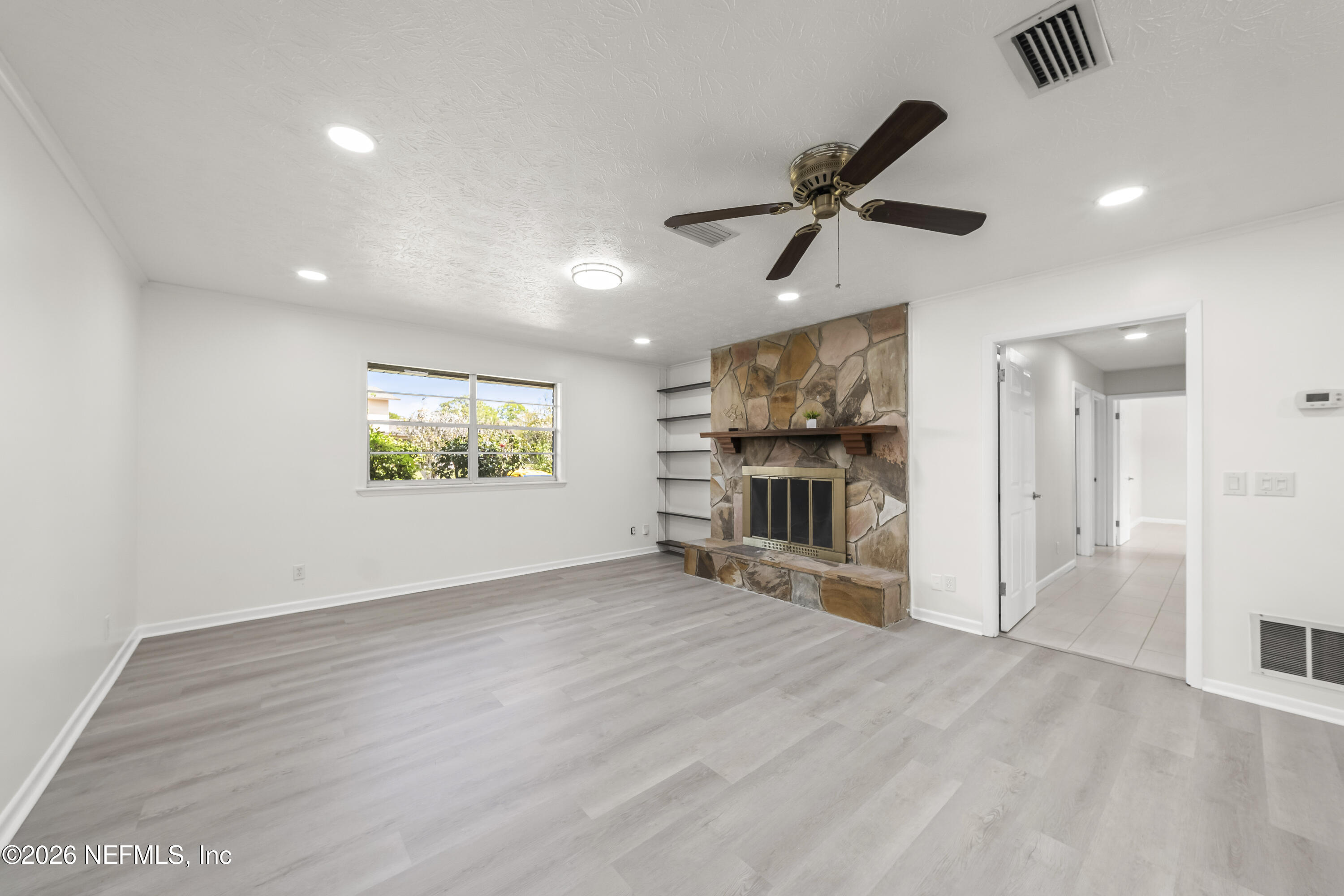 3571 Sandburg Road Jacksonville, FL 32277 - Photo 12 of 41 an empty room with wooden floor a ceiling fan and windows