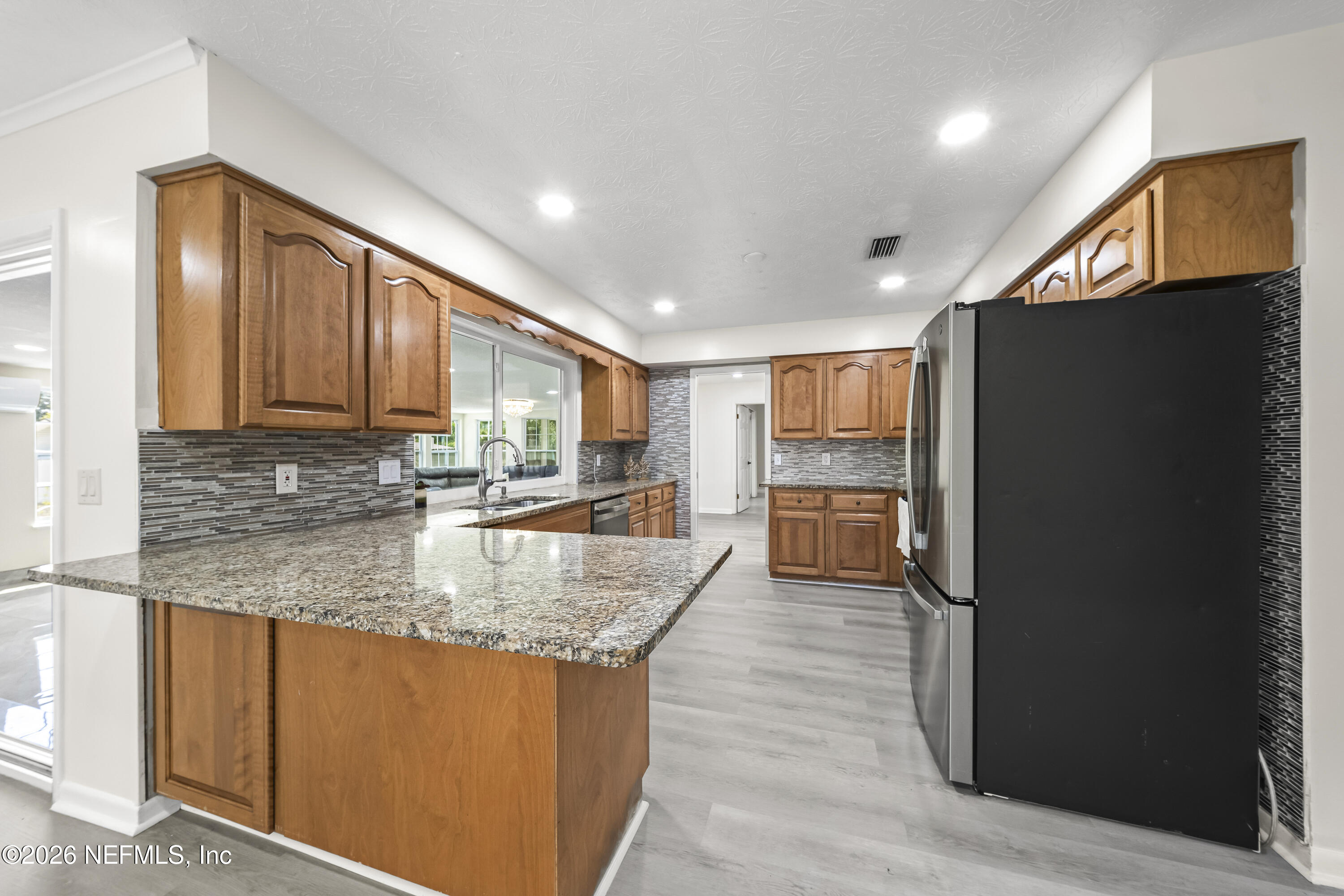 3571 Sandburg Road Jacksonville, FL 32277 - Photo 22 of 41 a large kitchen with stainless steel appliances granite countertop a refrigerator a oven and a sink with wooden cabinets