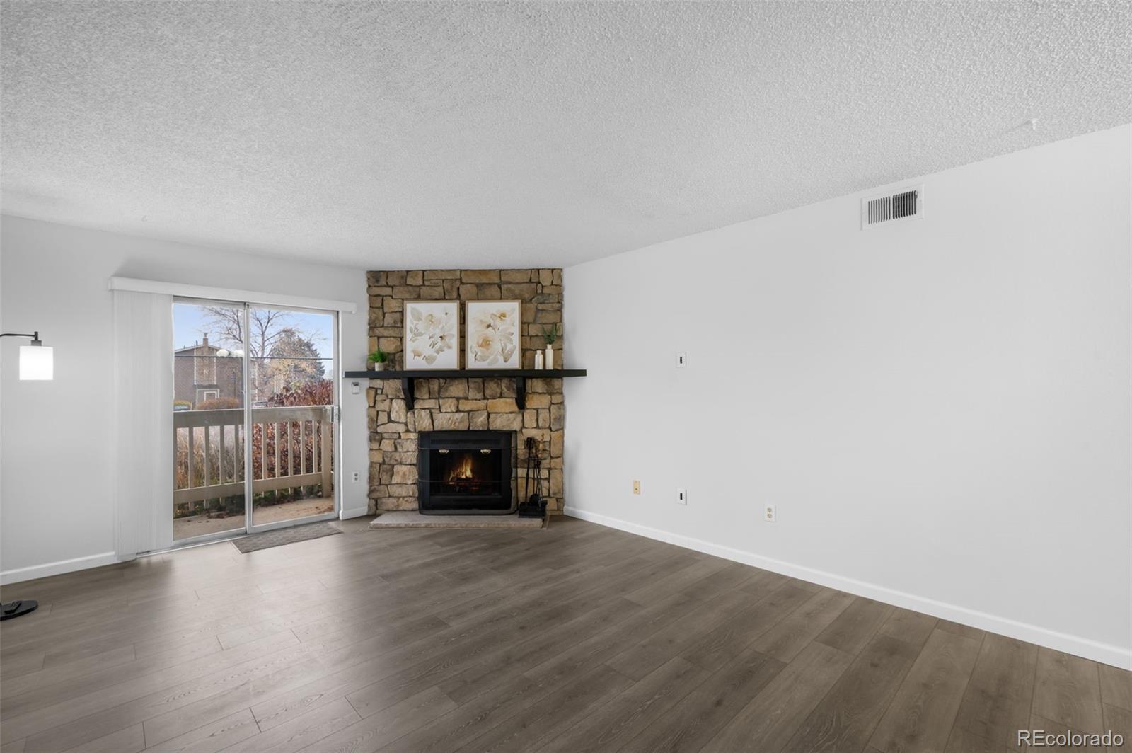 4400 South Quebec Street, Unit 102V Denver, CO 80237 - Photo 6 of 21 an empty room with wooden floor fireplace and cabinet