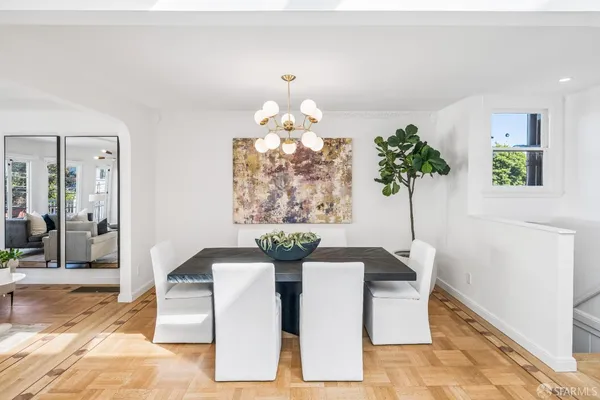 a dining room with chandelier and wooden floor