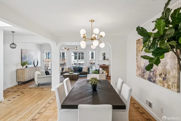 a living room with dining table furniture a potted plant and a large window