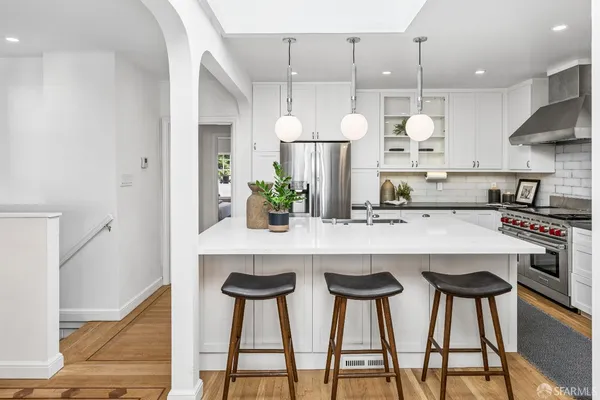 a kitchen with stainless steel appliances a dining table chairs and white cabinets