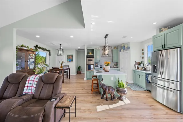 a living room with furniture dining table a refrigerator and kitchen view