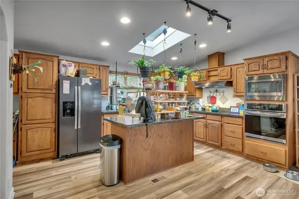 a kitchen with stainless steel appliances granite countertop a refrigerator a stove and a wooden floors