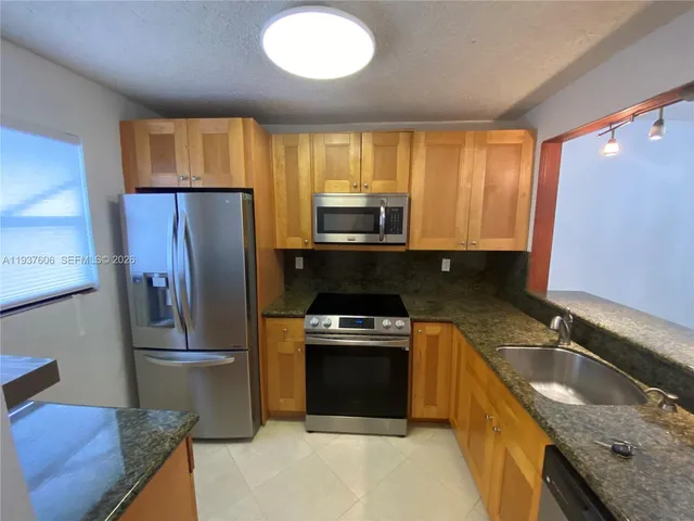a kitchen with granite countertop a refrigerator stove and sink